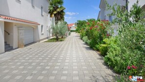 Eine Wohnstraße mit weißen Gebäuden, einem gepflasterten Gehweg und Grünflächen.