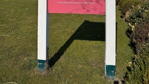 A sign with text indicating a location for 'Gastezimmer' and 'Ferienwohnungen' with a green and red color scheme.
