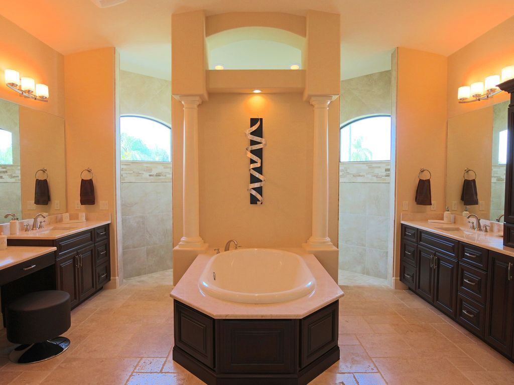A spacious bathroom with a large bathtub, two sinks, and dark cabinetry.