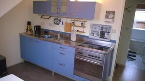 A compact kitchen with blue cabinets, a stainless steel stove, and a sink.