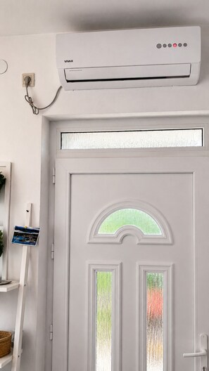 A white door with a frosted glass window, a VIVAX air conditioning unit mounted above it, and a wall-mounted light switch to the left.