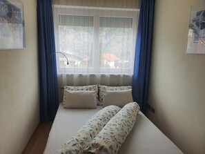A room with a bed, a window with curtains, and a wall-mounted lamp. - Apartment Wilhelm (Sautens)
