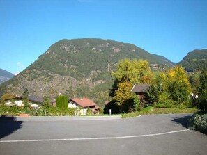 A parking lot with a mountain in the background, surrounded by houses and greenery.