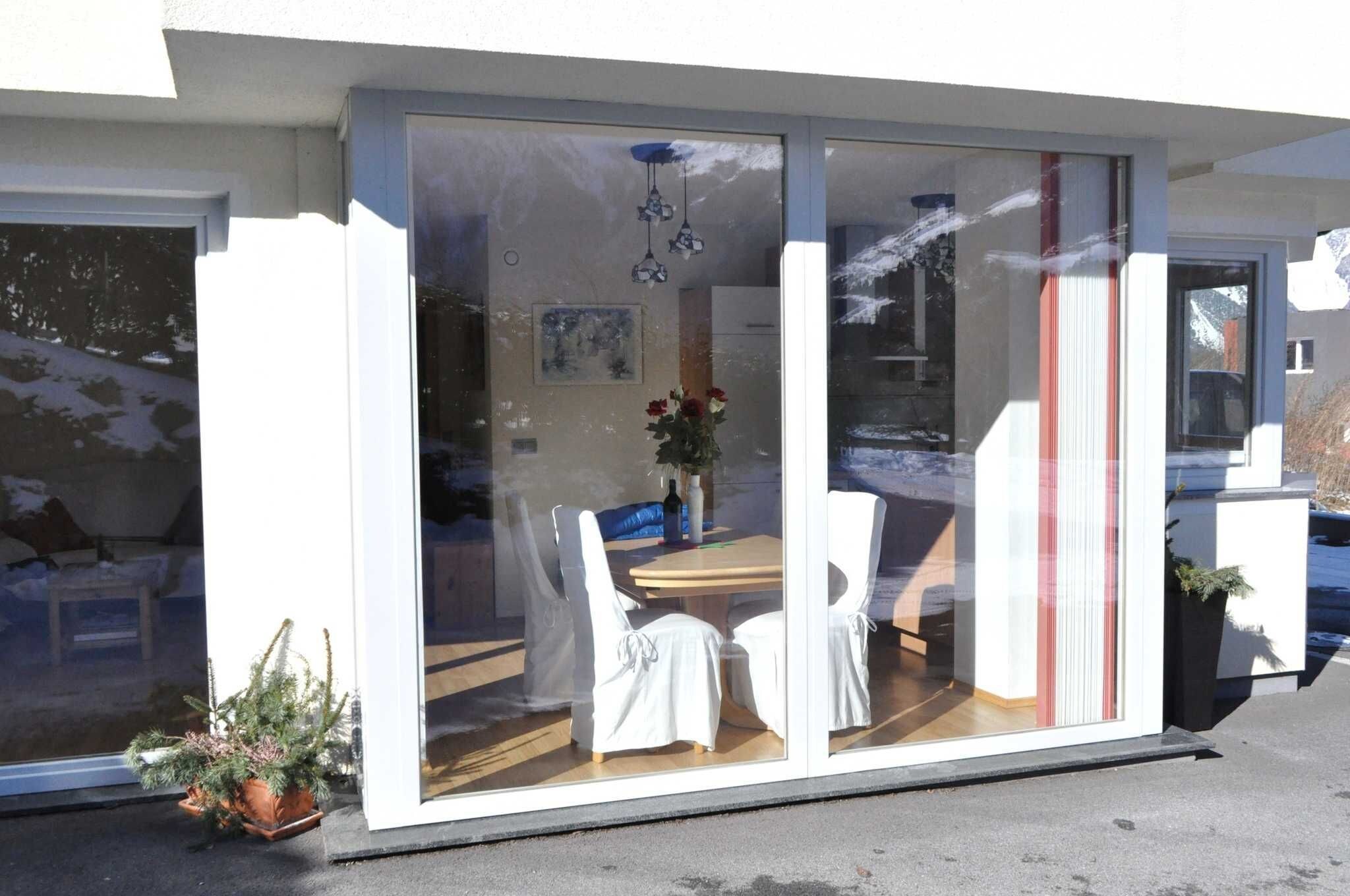 A modern house with a sliding glass door leading to a dining area with a table and chairs.