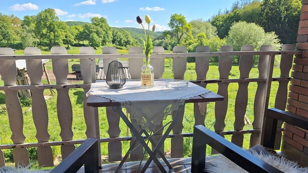 Une terrasse avec une table, des chaises et une vue sur un paysage verdoyant.