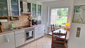 Une cuisine moderne équipée d’un four, d’un micro-ondes et d’un évier intégrés. Un coin repas avec une table et des chaises est également disponible.