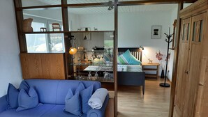 Un salon avec un canapé bleu, un plancher en bois et une vue sur la cuisine.