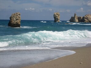 A beach with waves and rock formations.