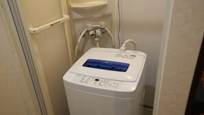 Un condizionatore portatile bianco e compatto, dotato di display digitale e pannello di controllo, posizionato in un piccolo bagno con lavandino bianco e portasci.