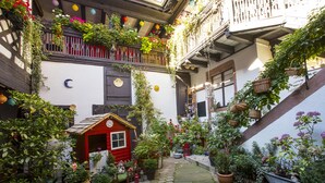 Ein Innenhof mit einem roten Spielhäuschen, Pflanzgefäßen und einer Treppe.