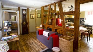 Ein gemütliches Wohnzimmer mit einer Couch, einem Holztisch, einer Uhr und einem durch einen offenen Durchgang erreichbaren Küchenbereich.