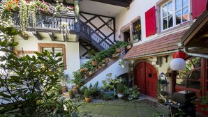 Ein Innenhof mit einer Holztreppe, Kübelpflanzen und einem Grill.