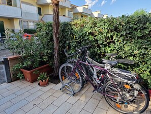 Bicycle parked against a wall, surrounded by lush foliage and a potted plant.