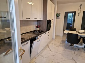 Kitchen features a stove, sink, and dish rack, adjacent to a dining area with a table and chairs.