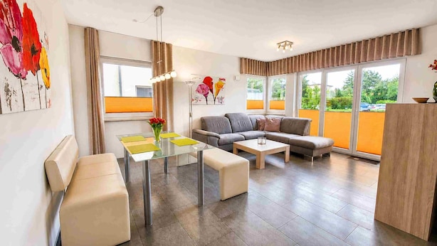 Ein modernes Wohnzimmer mit einer Couch, einem Glastisch und Blick ins Grüne.