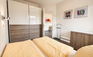 A hotel room with a bed, a wardrobe, a mirror, and a bathroom visible through an open door.