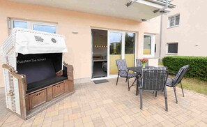 An outdoor seating area with a grill, wicker chairs, and a table.