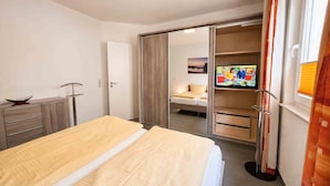 Ein Hotelzimmer mit Bett, Schrank, Fernseher und einem Fenster mit Jalousien.