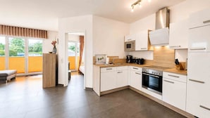 Eine moderne Küche mit weißen Schränken, einem Backofen und einer Mikrowelle.