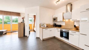 A modern kitchen with white cabinetry, a built-in oven, and a microwave. - Apartment AS04 - Villa hill (Heringsdorf)