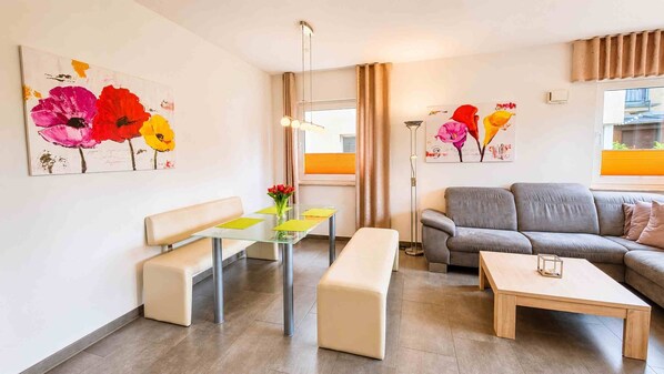 A modern living room with a sofa, a coffee table, a bench, and a glass table with a vase of flowers.