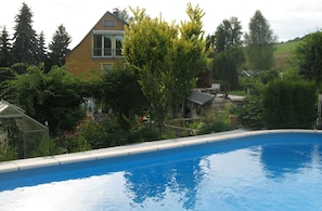 A swimming pool with a house in the background. - Vacation in Saxon Switzerland Garden Pool Stove Sauna (Sebnitz)