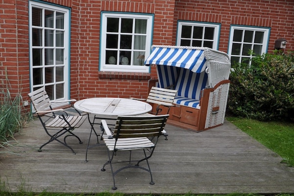 Die großzügige Terrasse mit Strandkorb, Teak Tisch und Stühlen und Grill