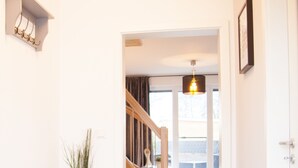 A hallway with a bench, a staircase, and a door leading to a balcony. - New: Luxurious apartment with lake view & garden [Nr. 2] (Storkow (Mark))