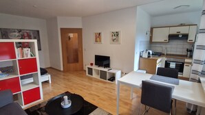 Una sala de estar moderna con televisor, comedor y cocina.