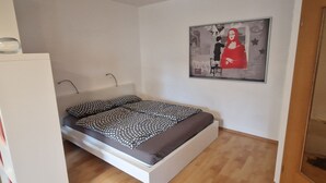 Un dormitorio con cama, un armario blanco y un cuadro en la pared.