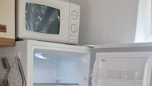 Una cocina con microondas integrado, refrigerador con congelador y encimera de madera.