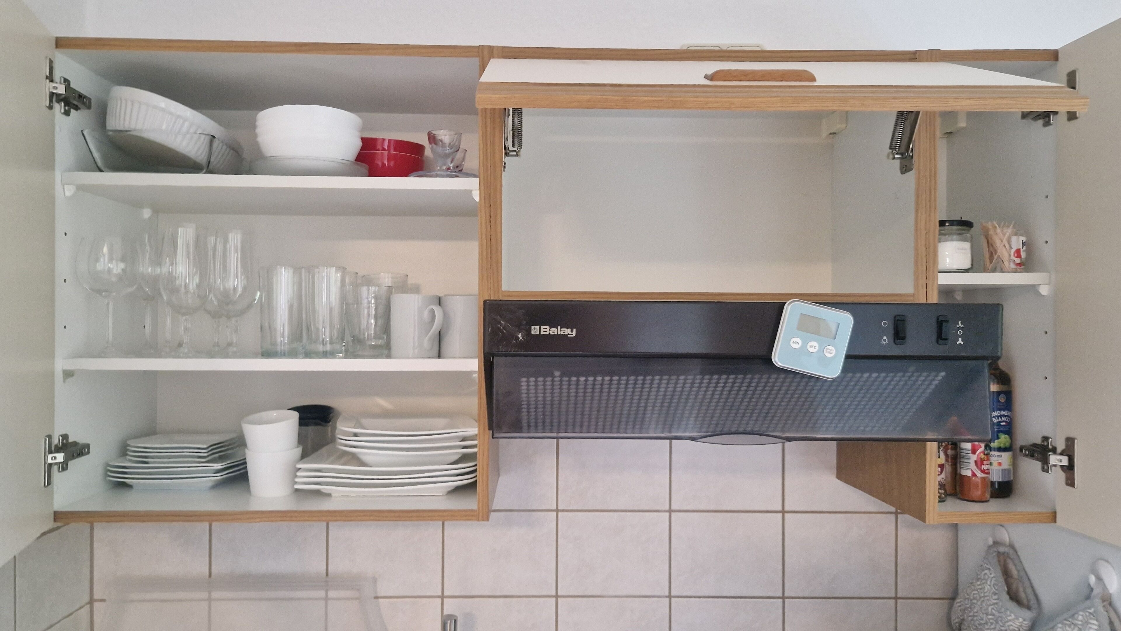 Una cucina con un forno a microonde Balay, mobili bianchi e diversi utensili da cucina.