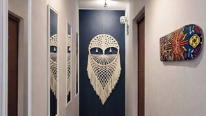 Un pasillo con un tapiz de macramé, una cámara de seguridad y una obra de arte colorida en la pared.