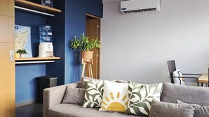 Una sala de estar moderna con un sofá, una mesa de centro, un mapa, un dispensador de agua y una planta en maceta.
