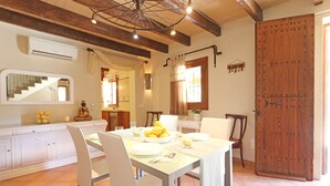 Uma área de refeições com uma mesa posta para quatro pessoas, cadeiras brancas, uma tigela de limões e um espelho sobre a mesa.