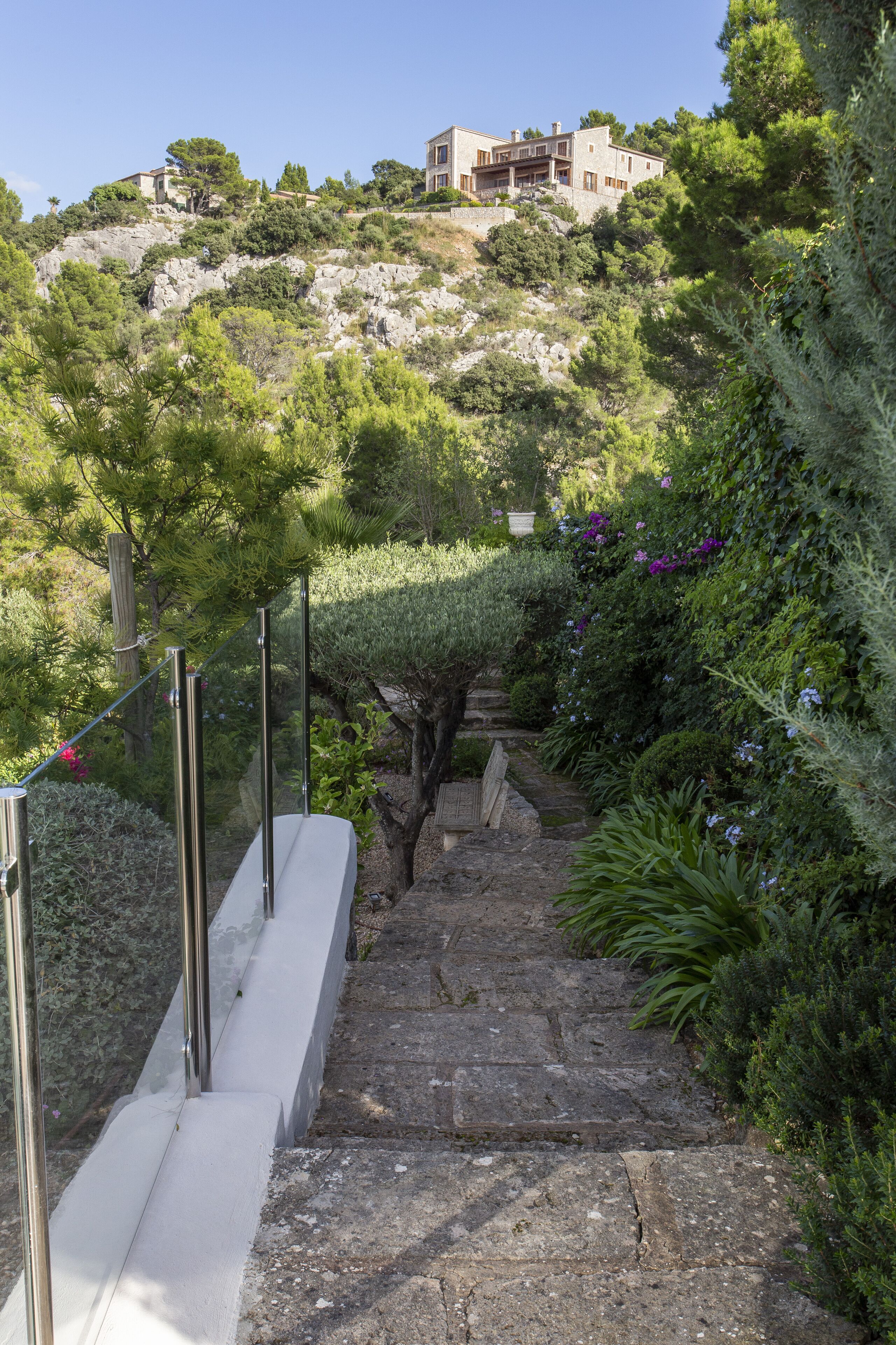 A stone staircase leading up a hill with a house in the background.