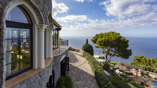 Un bâtiment en pierre doté de grandes fenêtres et d’un balcon offrant une vue sur la côte.