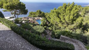 Un jardin aménagé avec une piscine, un chemin de pierre et une vue sur la mer.