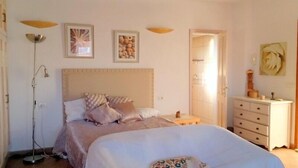 Ein Schlafzimmer mit einem großen Bett, Nachttischen, einem Kleiderschrank und einer Tür zu einem Badezimmer.