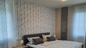 A bedroom with a large bed, a nightstand, a wall clock, and a rug. - Beautiful vacation rental in Bitburg-Stadt, with its own outdoor relaxation area (Bitburg)