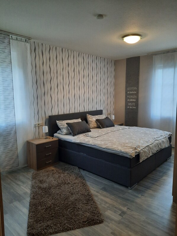A bedroom with a large bed, a nightstand, a wall clock, and a rug. - Beautiful vacation rental in Bitburg-Stadt, with its own outdoor relaxation area (Bitburg)