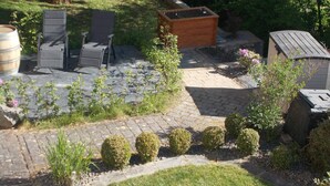 A patio area with a stone floor, surrounded by small bushes and a wooden planter. - Beautiful vacation rental in Bitburg-Stadt, with its own outdoor relaxation area (Bitburg)