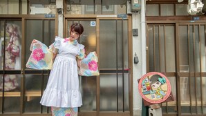 A person in traditional attire standing in front of a building with a sign indicating the address 18-17. - RetroChaya1 (Osaka)
