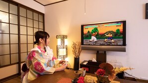 A person playing a video game on a television in a room with traditional decor. - RetroChaya1 (Osaka)