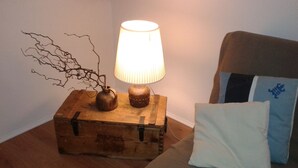 Une table de chevet en bois avec une lampe et deux vases, un coussin blanc et un coussin bleu sur un canapé.