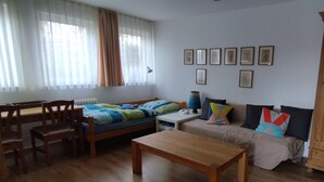 Une pièce confortable avec un lit, une table en bois, un canapé, une armoire et une fenêtre avec des rideaux.
