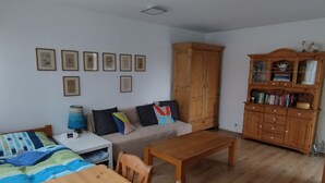 Une pièce comprenant un lit, une petite table, un canapé, une armoire en bois et des tableaux encadrés accrochés au mur.