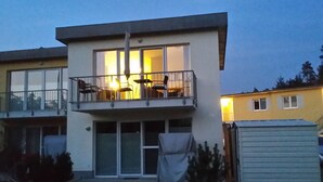 En toetages boligbygning med balkon, store vinduer og en overdækket terrasse.