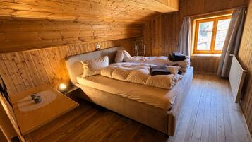 Ein Zimmer in einer Holzhütte mit einem Bett, einem kleinen Tisch und einem Fenster.