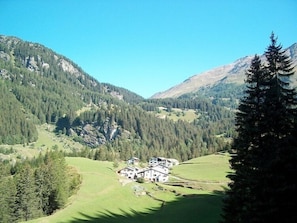 Eine Berglandschaft mit einer Ansammlung weißer Gebäude, umgeben von grünen Feldern und dichten Wäldern.